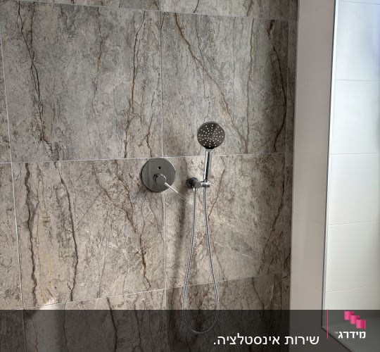 ראש מקלחת על קיר אריחים באמבטיה